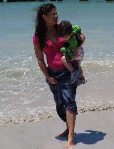 May Ting carrying her son on the beach